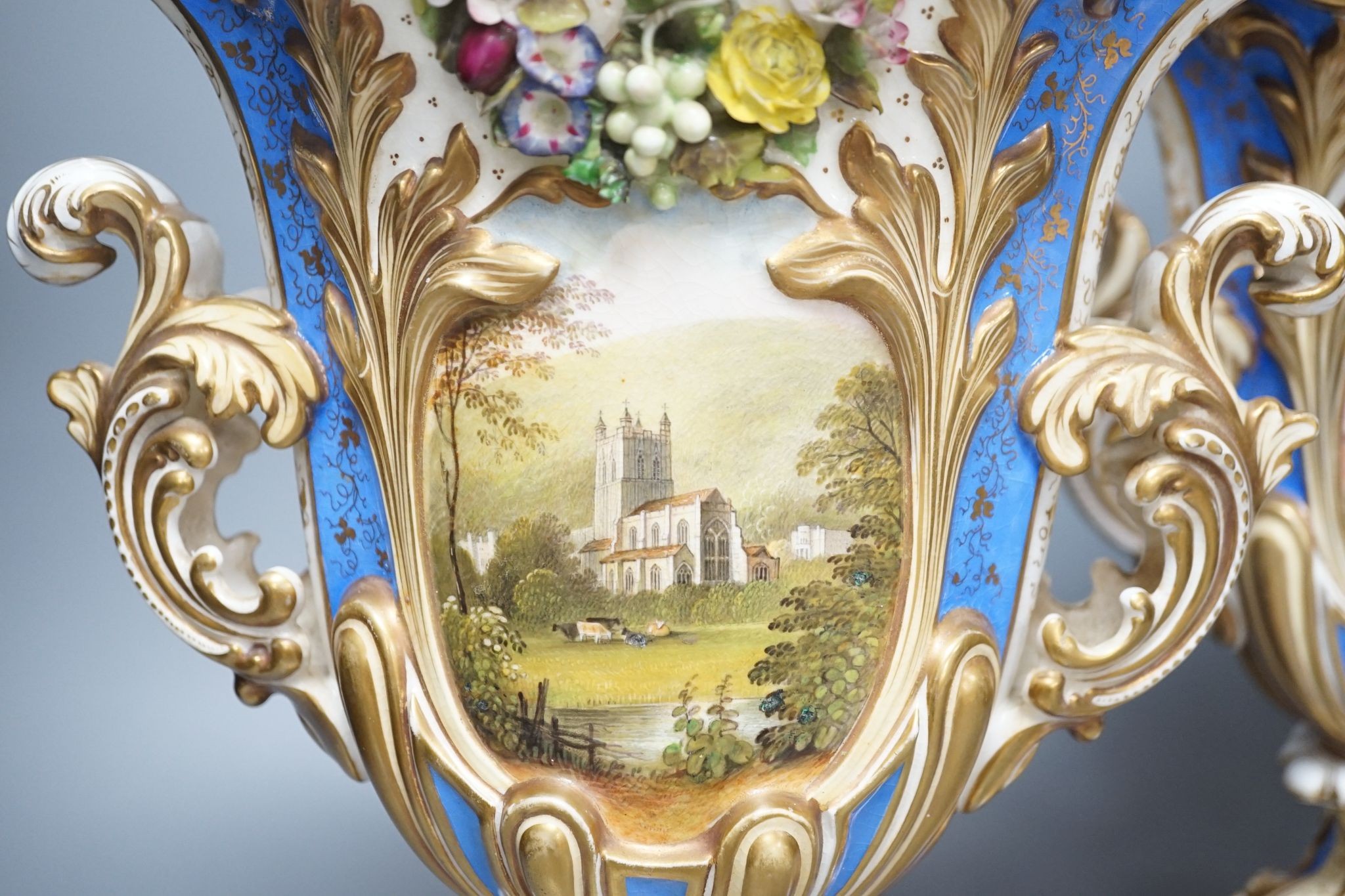 A large pair of 19th century Grainger & Co. vases with scenes of Worcester and Malvern on a blue ground, 34 cms high.